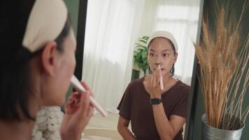 Woman Applying Foundation on Nose with Brush in Front of Mirror video