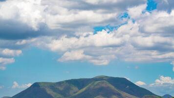 Time lapse of white clouds and blue sky with mountains, nature view during the day. Climate and weather concept video