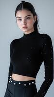 The model wears a black rib knit top with pearls photo