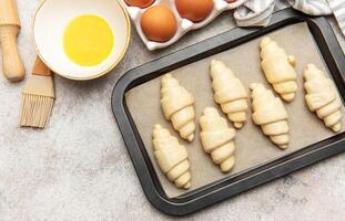 Baker preparing croissants on baking tray for baking photo