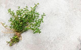 Fresh thyme bunch tied with twine on gray background for culinary use photo