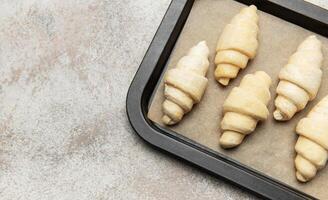 Raw croissant resting on baking sheet awaiting oven's warmth photo