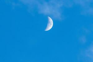 Crescent moon on clear blue sky with soft clouds in evening spring,Image close up view with details of the moon surface, natural astronomic photo