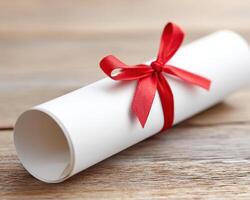 Rolled diploma scroll tied with red ribbon on wooden surface, symbolizing achievement and celebration in education or ceremony photo