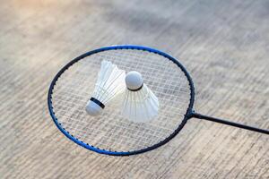 2 shuttlecocks on the net of a badminton racket on cement background, concept for outdoor badminton playing in free times, soft and selective focus. photo