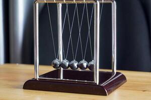 the Newtons cradle is a device that demonstrates the conservation of momentum and the conservation of energy with swinging spheres. Soft and selective focus. photo
