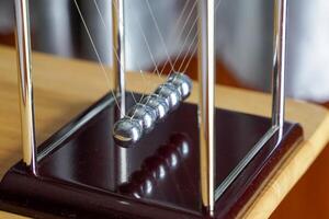 Newtons cradle is a device that demonstrates the conservation of momentum and the conservation of energy with swinging spheres. Soft and selective focus. photo