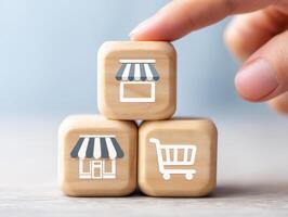 Hand stacking wooden cubes with storefront and shopping cart icons symbolizing retail and commerce concepts in soft light photo