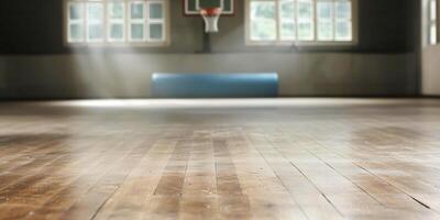 A wooden basketball court floor is seen from a low angle, with sunlight streaming through windows. The hoop is visible in the background, adding depth. photo