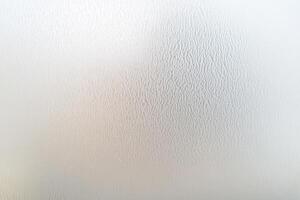 Close-up view of a textured white surface, possibly a wall or appliance, with light variations photo