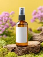 Amber spray bottle with blank label on mossy wood, blossoms, and a yellow backdrop. Product showcase photo