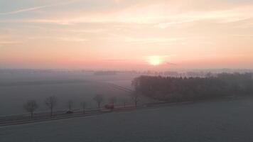 A sunrise over a field with trees and a road video