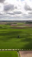 Aerial view of a field with a windmill in the distance video