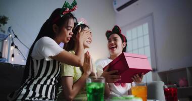 Handheld low angle view shot, One friend blindfolds the birthday person, and the other holds a gift to prepare a surprise in a joyful atmosphere. video
