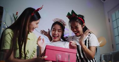 Handheld low angle view shot, One friend blindfolds the birthday person, and the other holds a gift to prepare a surprise in a joyful atmosphere at home. video