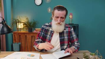 POV shot of senior man looking to camera listening to colleague talking writing down notes on diary video