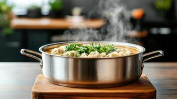 A pot of soup with vegetables and herbs on a wooden table photo