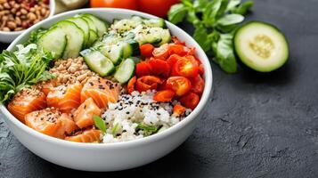 Salmon, rice, cucumber, tomatoes and other vegetables in a bowl photo