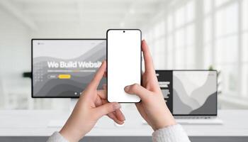 Smartphone mockup held in hands in office setting, with computer and laptop in background, ideal for corporate app design presentation photo