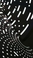 An intriguing low-angle shot captures a dynamic abstract pattern formed by bright light filtering through a perforated surface onto a dark, curved tunnel. The interplay of luminous dots and dashes video