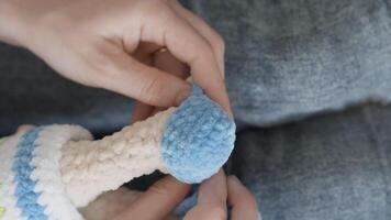 This closeup shows a skilled artisan meticulously attaching a colorful knitted ball to a handmade toy, showcasing exceptional craftsmanship and dedication that inspire this beloved craft video