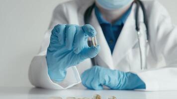 A healthcare worker with gloves showcases different capsules, analyzing their properties, emphasizing the importance of safety and health in clinical settings where patients receive care video