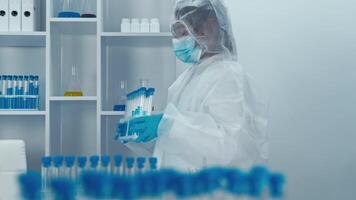en un alta tecnología laboratorio, un diligente científico en protector engranaje hábilmente manejas prueba tubos y avanzado instrumentos mientras demostrando varios procedimientos y en marcha investigación ocupaciones video