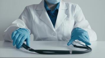 A dedicated healthcare professional in a crisp lab coat and gloves interacts with a stethoscope in a modern workspace, symbolizing readiness for patient care and commitment to medical service video