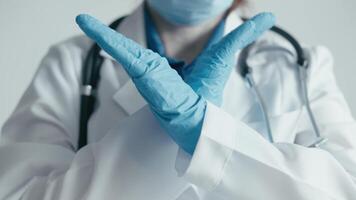 In a medical setting, a professional in a lab coat and gloves uses hand gestures to emphasize the importance of health awareness and preventive measures during the ongoing pandemic video