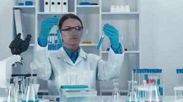 un enfocado científico inspecciona diferente prueba tubos en un alta tecnología laboratorio. el escena vitrinas meticuloso investigación y análisis, enfatizando el importancia de científico consulta. video