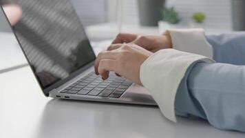 A closeup view of hands typing on a sleek laptop in a stylish workspace adorned with greenery, blending technology with a serene atmosphere perfect for productivity video