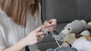 uma focado mulher é habilmente crochê uma encantador pelúcia brinquedo enquanto ser cercado de a matriz do colorida fio, refletindo a delicioso alegria do construindo dentro uma acolhedor e convidativo casa meio Ambiente video