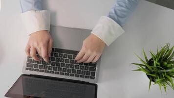 This image shows hands typing on a sleek laptop, highlighting productivity in a stylish office with lush greenery, emphasizing the blend of work and technology in a modern workspace video