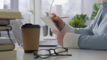 esta imagen muestra un persona tomando notas con un lápiz en un brillante oficina, destacando creatividad y productividad en un moderno lugar de trabajo dónde ideas fluir y inspiración combustibles éxito video