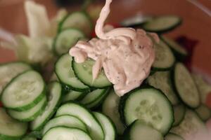 Cucumber slices topped with creamy dressing in a salad bowl ready for serving at a casual gathering photo