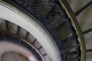 Intricate spiral staircase with faded elegance captured from above in a historic building photo