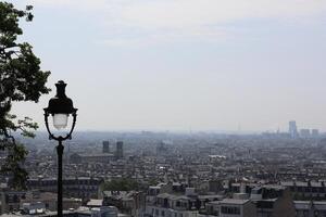 View of Paris skyline from a hillside with a vintage lamp post in the foreground on a clear day photo