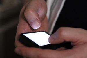 Hands using smartphone in dark indoor setting while engaging with digital content photo