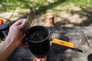 Enjoy the delightful experience of outdoor cooking imagine a pot simmering on a camp table set amidst breathtaking nature, creating an adventurous culinary journey under the vast open sky photo