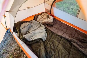 Experience the warmth and comfort of a cozy camping setup inside a vibrant colorful tent, complete with soft sleeping bags and warm blankets, perfect for relaxation and recreation in nature photo