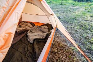 Imagine a cozy camping tent in a serene setting, surrounded by greenery. Inside, soft sleeping bags await, offering a perfect space for relaxation and adventure during your nature getaway photo