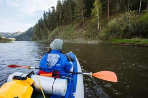 An adventurous kayaker is enthusiastically exploring a serene river, navigating through a stunning natural landscape filled with lush greenery, picturesque views, and a tranquil environment photo