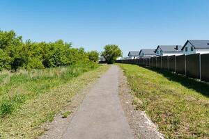 A winding path elegantly meanders through a lush, vibrant field situated in the beautiful countryside, where charming rustic houses and breathtaking views create an idyllic rural setting photo