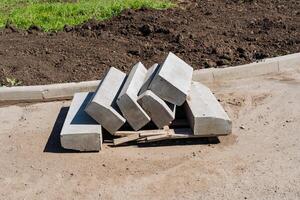 A substantial pile of grey concrete blocks has been carefully stacked on top of one another on the ground, creating a sturdy structure ideal for various building projects photo