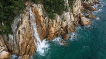 Majestic Waterfall Cascading Down Rocky Coastline Surrounded by Lush Greenery and Turquoise Ocean Waves photo