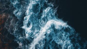 Aerial View of Roaring Ocean Waves Creating Dynamic Patterns with Stunning Blue Tones Over Dark Ocean Surface photo