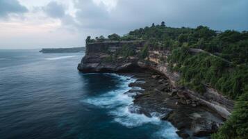 Serene Coastal Landscape with Cliffside Vegetation and Gentle Ocean Waves at Sunset in Bali, Indonesia photo
