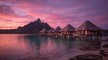 Sunset Overwater Bungalows with Mountain Background Under Colorful Sky in Tropical Paradise photo