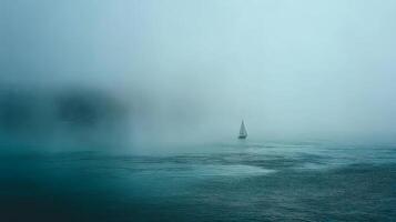 Tranquil solitary sailboat navigating through thick fog on calm water creating a serene and mysterious atmosphere photo