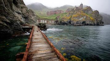 Abandoned Complex on Rocky Cliff Surrounded by Misty Waters and Overgrown Terrain in Serene Coastal Landscape photo